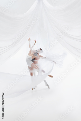фотографія Airborne dance partners create weightless pose inside white textile space