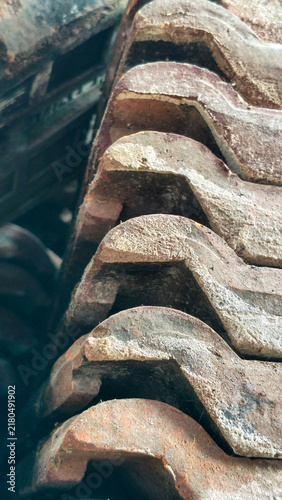 Stack of traditional weathered terracotta clay roof tiles. Close-up profile view of interlocking wavy ceramic pantiles for building.