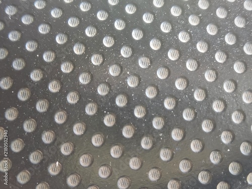 Close up photo of the surface texture of perforated black synthetic leather with a dotted pattern, suitable as a background.