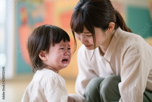 Obraz na płótnie 泣いている幼児にしゃがんで寄り添う若い日本人保育士