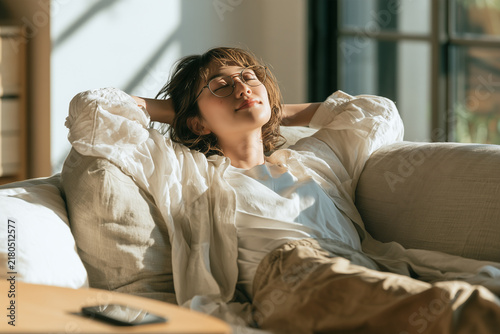 Obraz na płótnie 眼鏡をかけソファでリラックスし目を閉じる若い日本人女性、デジタルデトックス