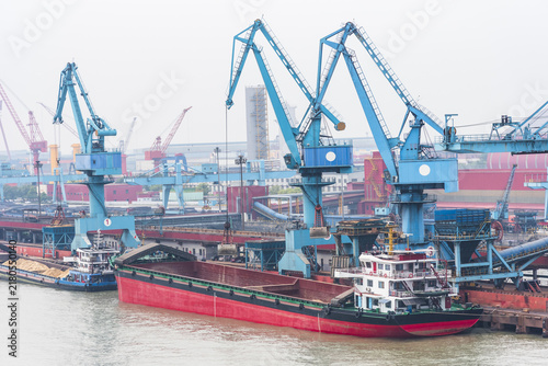 Photography River barge berthed alongside an industrial terminal near Shanghai during bulk cargo handling, highlighting river transportation, port operations and freight logistics
