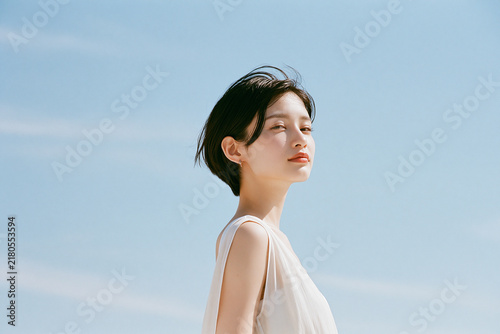 Naklejka 透明感のあるショートカットの女性。青空の背景。