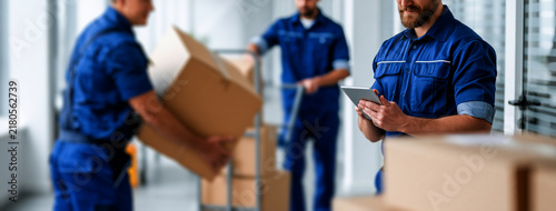 Professional movers in blue uniforms loading cardboard boxes