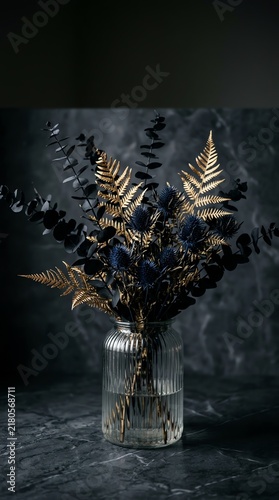 Luxury gold and black floral bouquet in glass vase. Elegant dark botanical home decor
