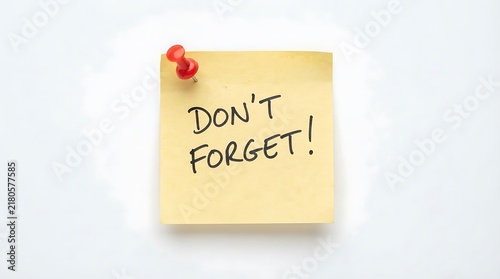 Yellow sticky note with the handwritten text message don't forget held by a red push pin for office reminders