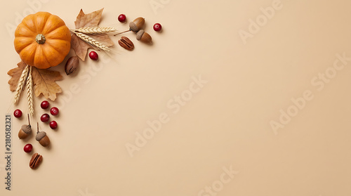 Autumn harvest composition features orange pumpkin wheat stalks brown acorns and red berries on beige background for thanksgiving seasonal social media.