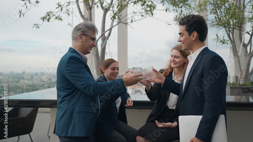 фотографія A group of diverse colleagues in business suits clink glasses together in a cele