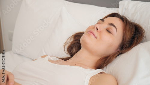 Quadro su tela A serene young woman rests peacefully on her back, eyes gently closed with a sof
