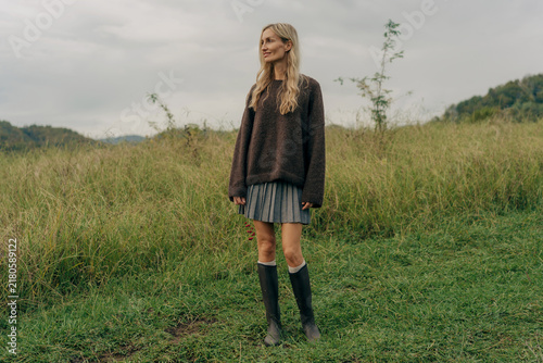 A portrait of a woman standing in an autumn meadow in the countryside.