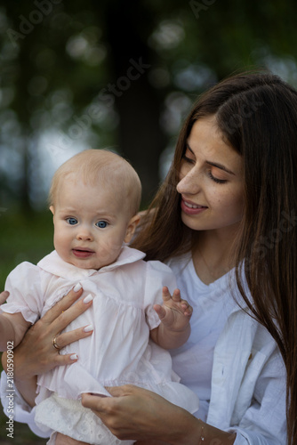 Young mother lovingly holding her baby daughter outdoors in soft natural light