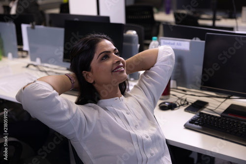 Canvastavla Indian working woman relaxing while break to sir on her desk, enjoying a serene moment at work
