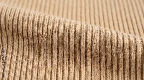Ribbed bamboo fabric texture background with soft folds and natural beige textile pattern.