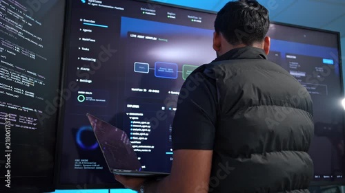 Dedicated software developer reviewing complex code on an expansive monitor in a contemporary tech workspace