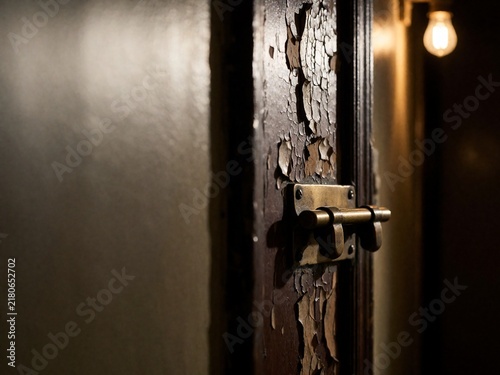 Old weathered door with peeling paint and brass bolt lock