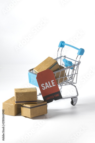 Shopping cart with delivery boxes and sale tag on white background