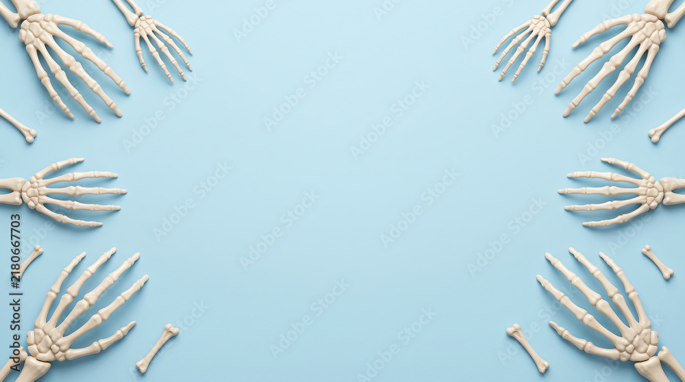 Fototapeta premium Multiple human skeleton hands arranged as a frame on a solid light blue background with copy space