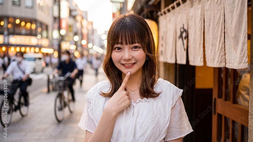 © Jesse_4160 - Happy young Japanese woman smiling and pointing at her chin on a busy Tokyo street in the evening with blurred bokeh background