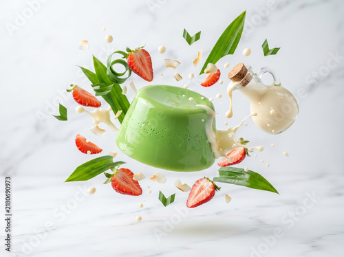 Levitating green pandan pudding with strawberries and coconut milk