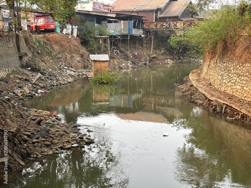 Konstfotografi Urban River Flowing Through Slum Settlement with Houses Built on Stilts