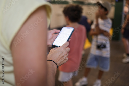 Fotografie Woman using smartphone while young children are nearby, highlighting screen addi
