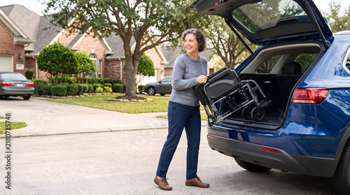 Woman loading a lightweight foldable wheelchair into an SUV for travel