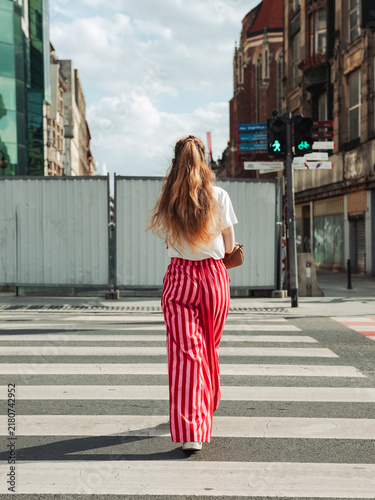 young woman in red trousers crossing at a pedestrian crossing