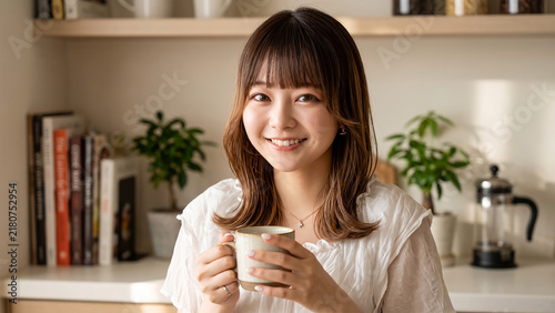 Happy young Japanese woman holding a coffee cup in a cozy kitchen with plants and books