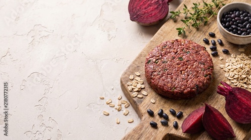 plant-based burger patty on wooden board with vegetables and grains
