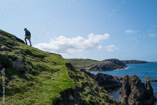 Male hiker walking up a headland on the coast of The Isle of Lewis.