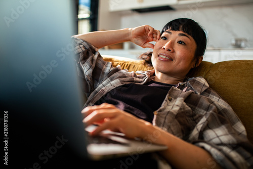 Smiling woman using laptop on couch at home