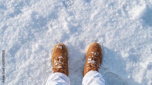 Top view of brown winter boots standing on fresh white snow in bright sunlight