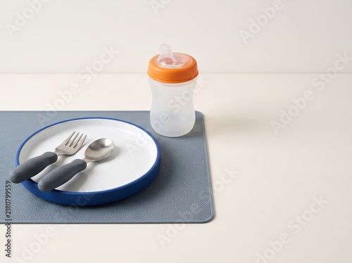 Toddler utensils and sippy cup arranged on silicone placemat