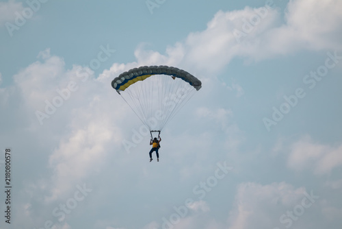 Canvastavla Parachutist in blue cloudy sky with yellow blue parachute, thrill of skydiving