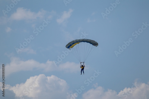 Foto Extreme skydiving action, parachutist glides with vivid yellow and blue parachut
