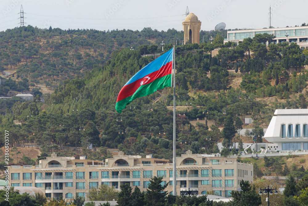 Obraz premium Baku city skyline with Azerbaijani flag waving proudly on a sunny day during the Formula 1 Grand Prix