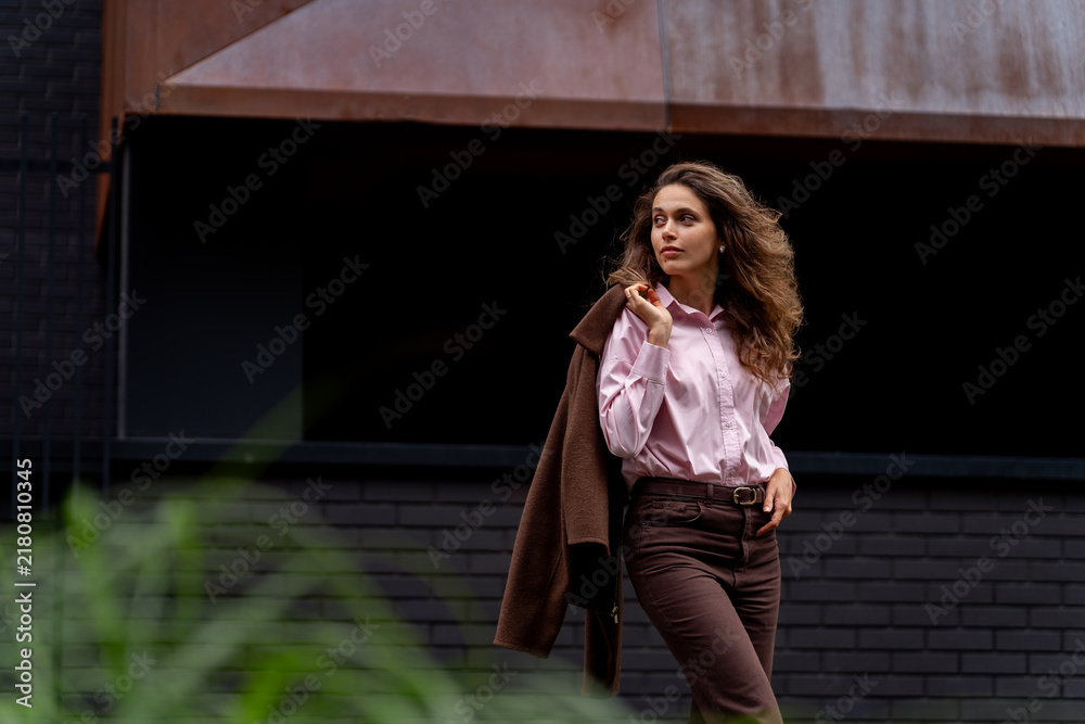 Fototapeta premium Young woman holding jacket over shoulder looking away outdoors