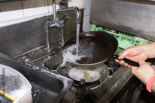 Rinsing soapy frying pan under running water tap