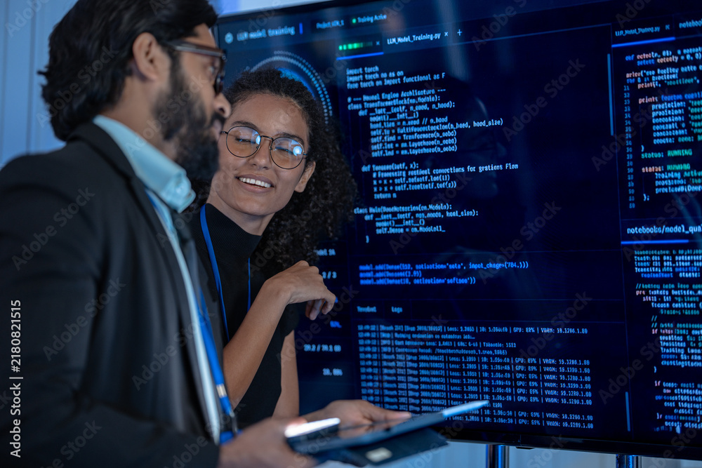 Fototapeta premium Two tech professionals examine a neural network visualization projected on a large display in a dark AI operations center.