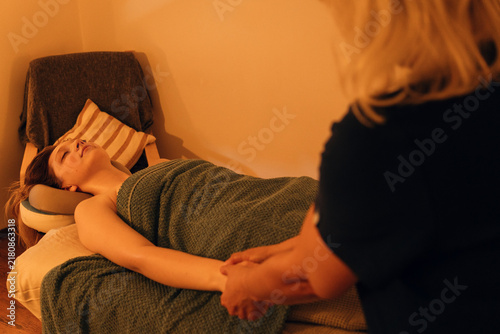 Foto Female massage therapist stretches and massages the arm of a woman lying on a massage table