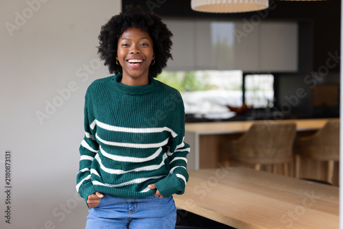 African American woman standing in kitchen wearing green striped sweater, hands tucked
