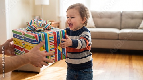 Joyful toddler receives a colorful birthday gift from parent indoors