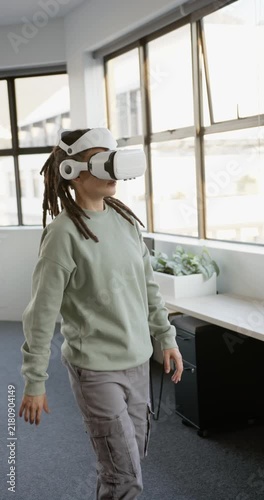 Vertical video: Non-binary adult in VR headset walking as VR starting, reaching VR scene by windows