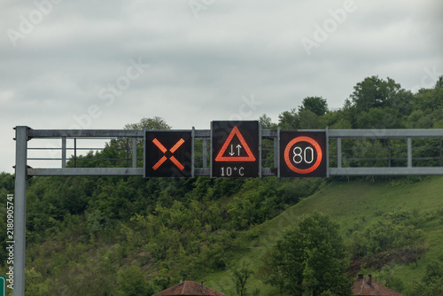 Overhead Electronic Traffic Signs Display Red X Warning Triangle and 80 Speed Limit on Rural Road