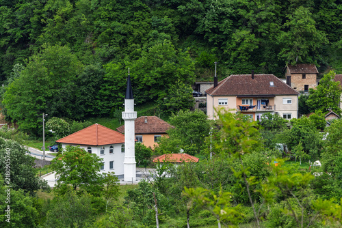 White Mosque With Tall Minaret in Green Hillside Village Surrounded by Houses and Forest, Jablanica, Bosnia And Herzegovina