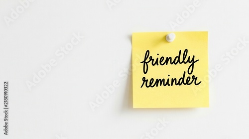 Handwritten friendly reminder on a yellow sticky note pinned to a white wall for communication and tasks.