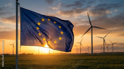 The EU flag with yellow stars flies in front of wind turbines at sunset.