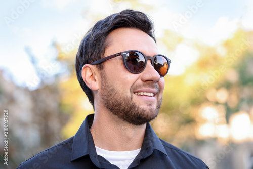 Handsome man wearing stylish sunglasses on city street