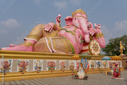 Giant reclining pink Ganesha statue and rat attendant sculpture at Wat Saman Rattanaram temple in Chachoengsao, Thailand.
