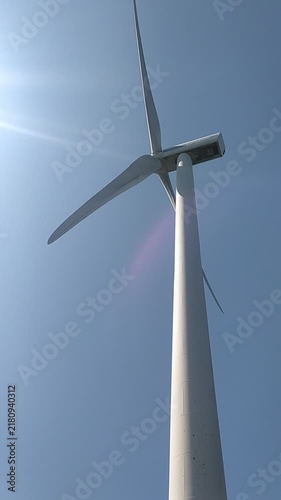 Lowangle shot of a towering white wind turbine against a clear blue sky, evoking a strong sense of hope and a clean, sustainable future. Perfect for ecofriendly designs nobody.